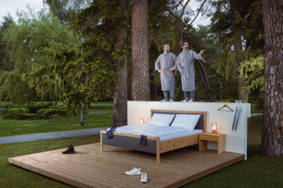 Frank und Patrik Riklin präsentieren ihr Null-Stern-Hotel im congresspark igls | © Florian Mitteregger Frank und Patrik Riklin posieren auf der Rückwand ihres Null-Stern-Hotels | © Florian Mitteregger