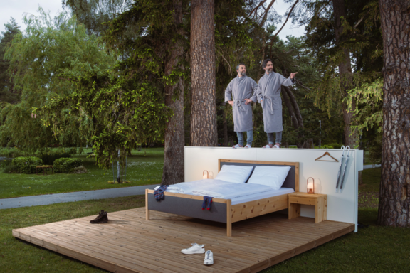 Frank und Patrik Riklin posieren auf der Rückwand ihres Null-Stern-Hotels | © Florian Mitteregger